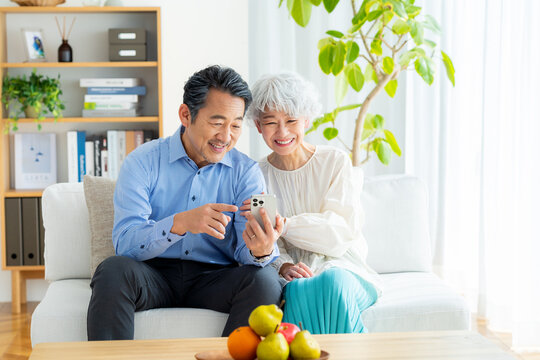 リビングでスマホを見るシニア夫婦