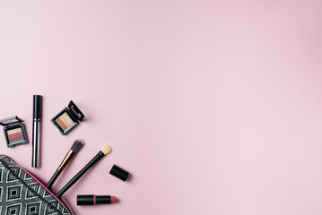 Cosmetics falling out of cosmetics on pink background