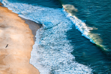 Atlantic ocean coast in Nazare, Portugal. Turquoise water and yellow sand at sunset.