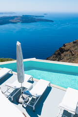 White architecture in Santorini island, Greece. Chaise lounges and swimming pool with sea view.
