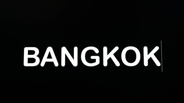 Close up of BANGKOK being typed into computer monitor screen with blinking cursor on black background copy space. Digital Words on the  LCD display.