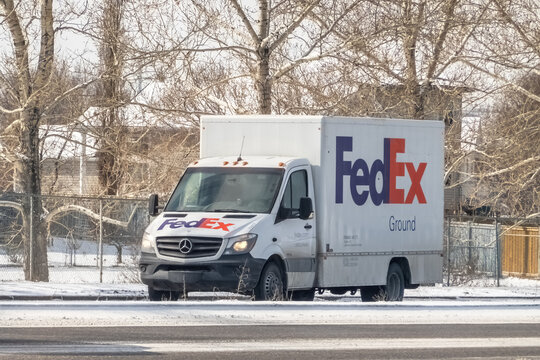 Calgary, Alberta, Canada. Feb 25, 2024. A FedEx Ground delivery shipping vehicle traversing a winter landscape on the roadway.
