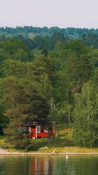 Panoramic View On Many Red Swedish Wooden Sauna Logs Cabvertical s Houses On Island Coast In Summer Cloudy Day. Swedish Old Tradition Wooden Houses. Bold Colors. Travel to Sweden.