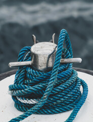 Close-up of mooring bollard with blue rope on a white ship