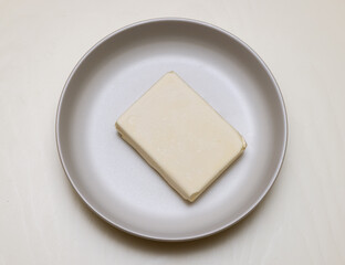 Preparation for kneading the dough. place a briquette of butter on a white plate to soften. view from above