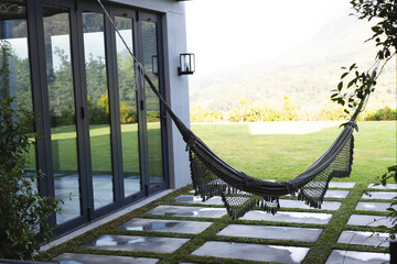 A black hammock hangs invitingly in a modern home's backyard with copy space