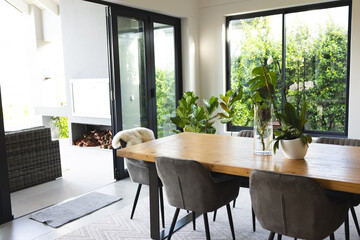 A modern dining room features a large wooden table with grey chairs and a fireplace, with copy space