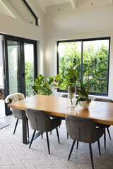 A modern dining room features a wooden table with gray chairs and a sleeping cat, with copy space
