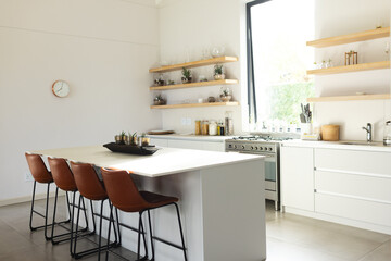 A modern kitchen features a central island with brown stools and white cabinetry, with copy space