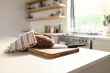 Freshly baked bread rests on a wooden cutting board in a bright kitchen, with copy space