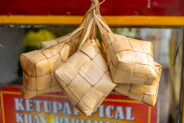 A bunch of steamed diamond shaped rice cakes hung for sale and prepared for servings