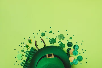 Foto op Aluminium Saint Patrick Day background with green decoration from shamrocks, leprechaun hat, golden coins and eyeglasses top view. © juliasudnitskaya
