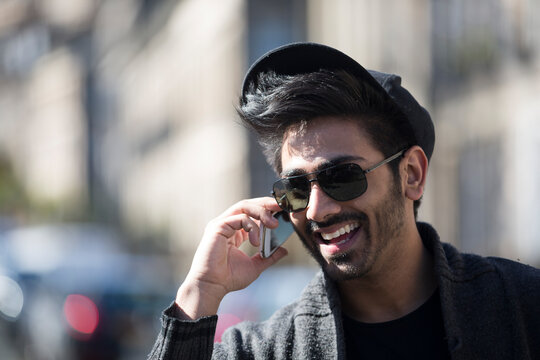 Indian Man standing in city takling on phone.