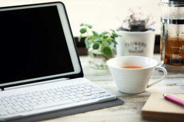 タブレット端末で仕事の合間にティーカップに注いだルイボスティー