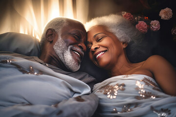 An elderly dark-skinned man and woman, a loving couple, are laying side by side together in bed