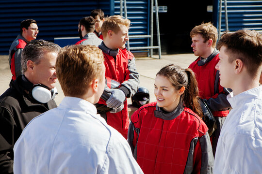Pit crew with team principle standing in the pit lane talking  
