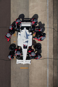 Over head racing car Pit crew in action during a tire change at a race track.  
