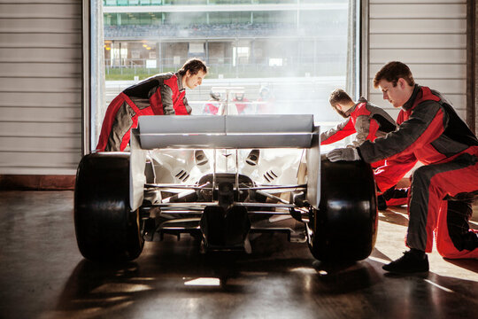 Pit crew working diligently on a race car in the garage.