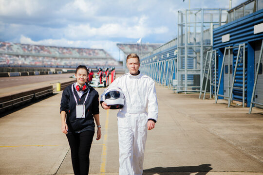 Race car driver and engineer walking on the track sidebyside. 