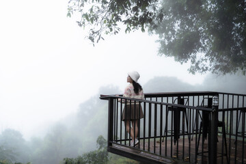 Asian Tourist women On the wooden walkway with Foggy forest Beautiful landscape Scenic view of misty mountain nature background. in Chiang Mai, Thailand