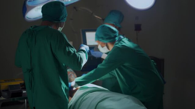 A professional medical team in the operating room helps the patient, performs CPR and uses an electrical defibrillator to shock the heart.