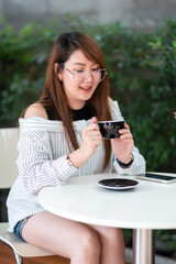 Portrait of beautiful happy Smiling asian woman relaxing and and smartphone sitting in cafe interior in coffee shop background