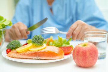Asian elderly woman patient eating salmon steak breakfast with vegetable healthy food in hospital.