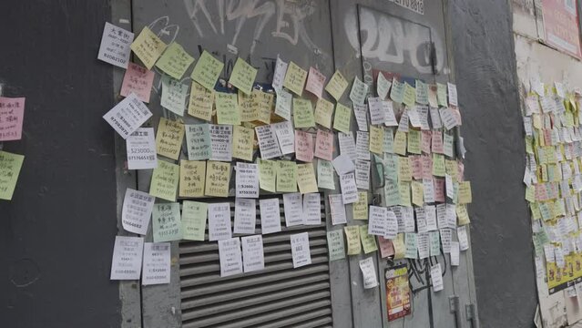 Static shot of messages in Chinese on colourful post it notes on street wall