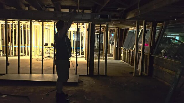 darkly lit scene pulling network cable through rafters during a building remodel