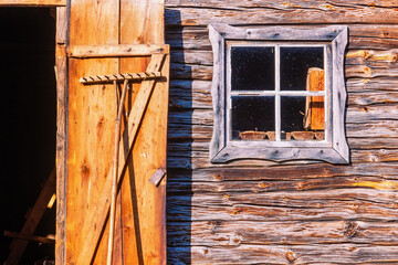 Rake stands against a door of an old barn - obrazy, fototapety, plakaty