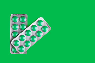two blisters with green tablets on a green background with a copy space - 747041428