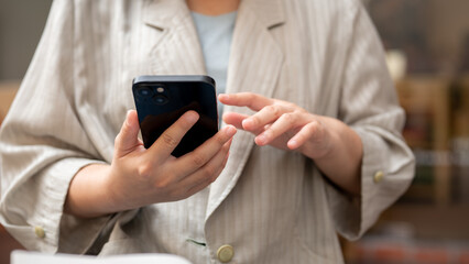 A cropped shot of a businesswoman reading messages on her smartphone, at a coffee shop.