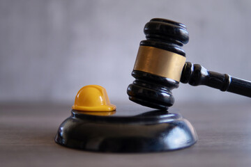 Closeup image of yellow hard hat and judge gavel. Labour law concept.
