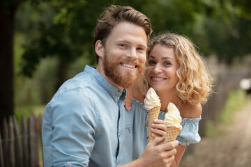 dating couple eating ice-cream sitting on city bench