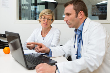 doctor and assistant looking at laptop