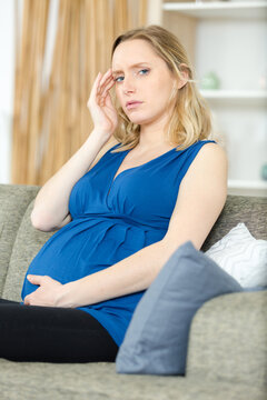 pregnant woman sat on the sofa suffering with a headache