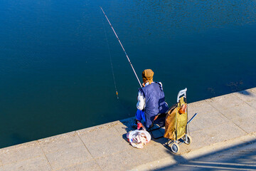 Woman fisherman catches fish with a fishing rod in autumn, summer or spring on the pier. Hobbies...