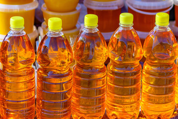 Row of bottles of fresh sunflower oil in selective focus at a farmers' market. Sale of natural vegetable or palm oil, sunflower oil shortage crisis.