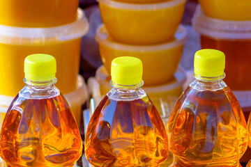 Row of bottles of fresh sunflower oil in selective focus at a farmers' market. Sale of natural vegetable or palm oil, sunflower oil shortage crisis.Close-up.