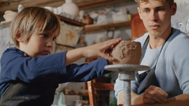 In the heart of the workshop, a young potter's hands dance on clay, traditional techniques birthing a handmade ceramic masterpiece.