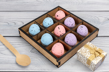 Colorful Easter eggs in a box and a gift box on the wooden background