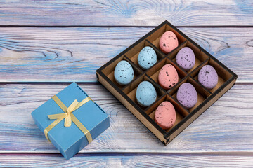 Colorful Easter eggs in a box and a gift box on the wooden background