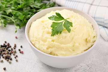 Bowl of tasty mashed potato, parsley,  and pepper on grey marble table