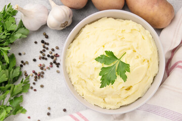 Bowl of tasty mashed potato, parsley,  and pepper on grey marble table