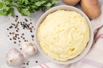 Bowl of tasty mashed potato, parsley,  and pepper on grey marble table