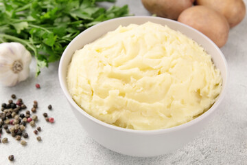 Bowl of tasty mashed potato, parsley,  and pepper on grey marble table