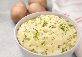 Bowl of tasty mashed potato, parsley,  and pepper on grey marble table