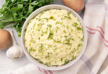 Bowl of tasty mashed potato, parsley,  and pepper on grey marble table