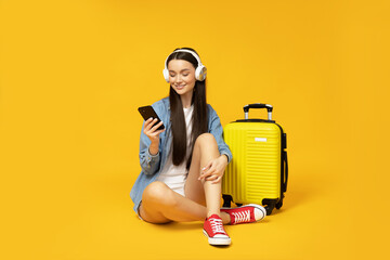 A young woman with a suitcase and a smartphone in her hands