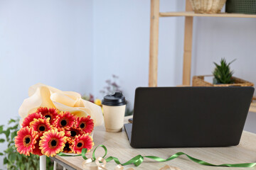 A florist's workplace, a bouquet, a laptop and a notebook.